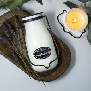 14 oz white candle in a glass jar with black lid and 'Eucalyptus Lavender' label on a wooden board, surrounded by lavender and a lit candle