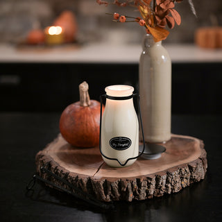 Milk bottle 'Hey, Pumpkin!' candle with pumpkins and a vase in the background