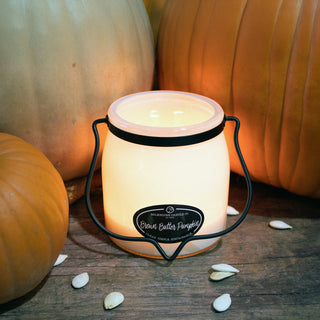 16 oz candle with a 'Brown Butter Pumpkin' label, pumpkins and seeds on a wooden surface