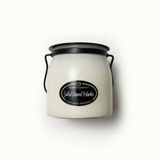 White candle jar with black lid and label on a white background