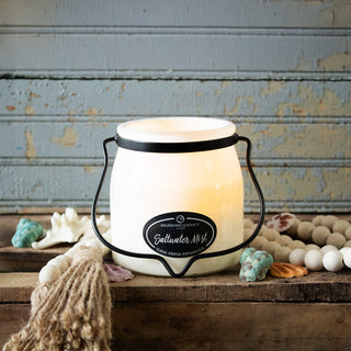 16 oz candle labeled 'Saltwater Mist' in a decorative container on a rustic wooden surface
