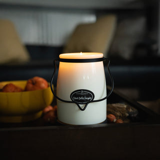 White 22 oz candle in a glass jar with a black handle and 'Brown Butter Pumpkin' label on a blurred background