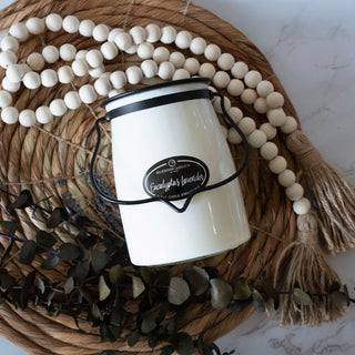 22 oz white candle with a black 'Eucalyptus Lavender' label on a woven mat with beads and tassels
