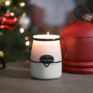 22 oz white candle with a 'Fireside Flannel' label in front of a blurred Christmas tree and red lantern