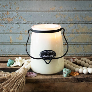 22 oz candle labeled 'Saltwater Mist' in a white container with black handle on a rustic wooden surface with decorative elements