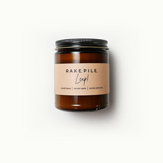 The Classic Collection candle in an amber jar with a 'Rake, Pile, Leap!' label on a white background