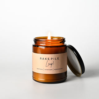 The Classic Collection candle in an amber jar with a 'Rake, Pile, Leap!' label on a white background