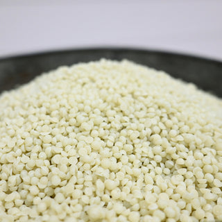 Close-up of pale yellow wax beads in a metal container