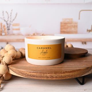 Candle with a 'Caramel Apple' label on a wooden surface in a kitchen setting