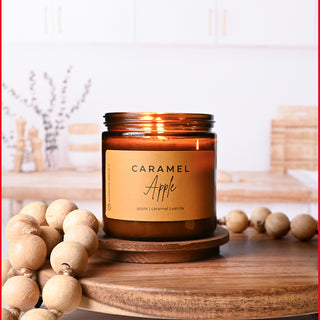 Caramel Apple candle on a wooden surface with decorative beads and a blurred background