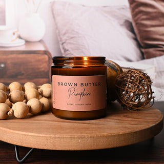 Brown Butter Pumpkin candle on a wooden surface with decorative elements.