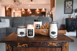 Four candles with labels on a wooden table in a living room setting