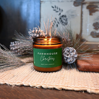 Candle labeled 'Farmhouse Christmas' with decorative elements on a textured surface