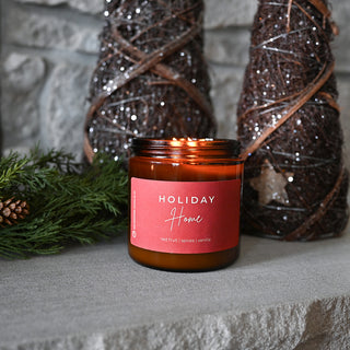 Candle with a red label labeled 'Holiday Home' on a stone surface with decorative elements.