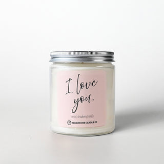 Candle in a clear jar with a silver lid labeled 'I love you.' on a light pink label against a white background