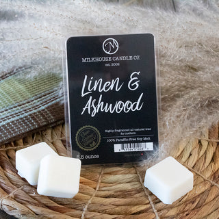 A packaged candle wax melt set labeled 'Linen & Ashwood' by Milkhouse Candle Co., shown with three white wax cubes on a woven mat.