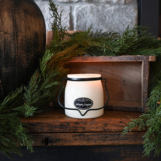 Decorative lantern with a candle on a wooden surface surrounded by greenery