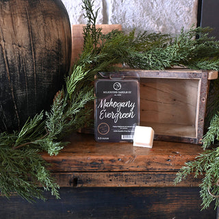Wax melts labeled 'Mahogany Evergreen' on a wooden surface with greenery
