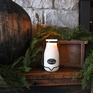 Vintage-style milk churn lamp on a wooden surface with greenery and a stone wall in the background