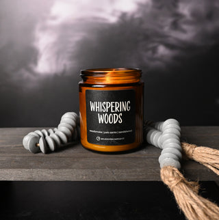 Candle jar labeled 'Whispering Woods' on a wooden surface with a dark background