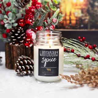 Candle labeled 'Winterberry Spice' with holiday decorations in the background