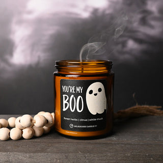Candle jar with a ghost label labeled 'You're My Boo' on a dark background
