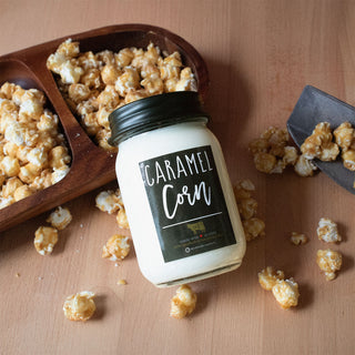 'Caramel Corn' candle with a wooden scoop and scattered popcorn on a wooden surface