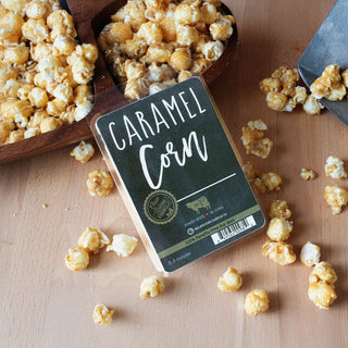 Wax melt package with a 'Caramel Corn' label on a wooden surface with caramel corn