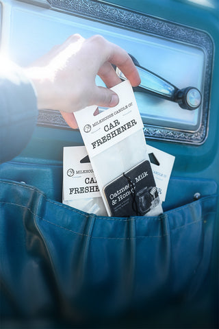 Hand holding car freshener cards with a blue vehicle interior background