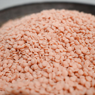 Close-up of pink wax beads in a metal container