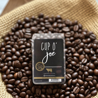 Cup O' Joe wax melt package surrounded by coffee beans on a woven mat