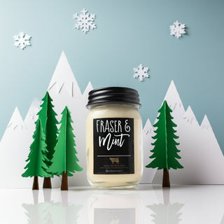 Candle labeled 'Fraser & Mint' with Christmas-themed decor including trees and snowflakes