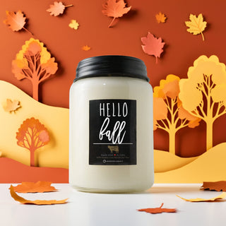Candle with 'Hello Fall' label against an autumn-themed background with leaves and trees