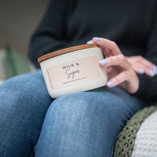 Person holding a 10 oz 'Milk & Sugar' candle in their lap