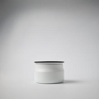 A white traveler tin with a black metal lid against a white background