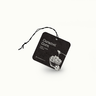 Black air freshener tag with 'Caramel Corn' text and an illustration of caramel corn on a white background