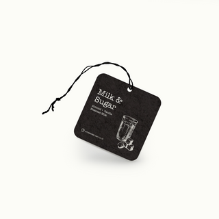 Black air freshener tag with 'Milk & Sugar' text and milk & sugar cubes illustration on a white background