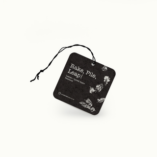Black air freshener tag with white text and leaves on a white background