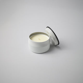 White candle in a tin with a lid on a gray background
