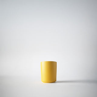 A yellow votive in front of a white background