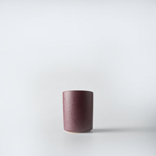 A burgundy flecked votive against a white background