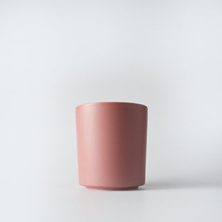 A blush colored ceramic container against a white background