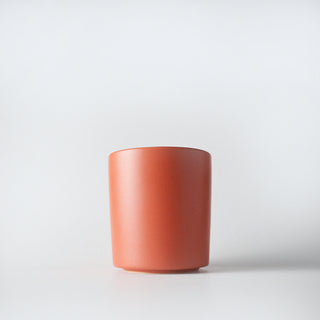 A coral colored ceramic container against a white background