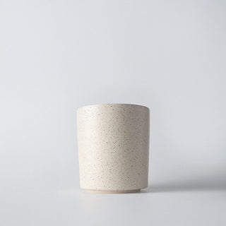 A cream speckled ceramic container against a white background 