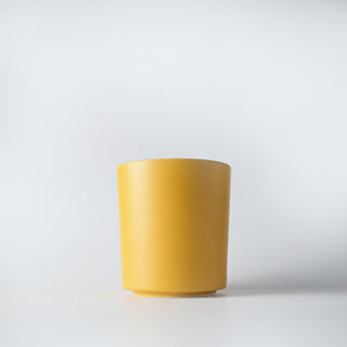 A yellow colored jar infront of a white background