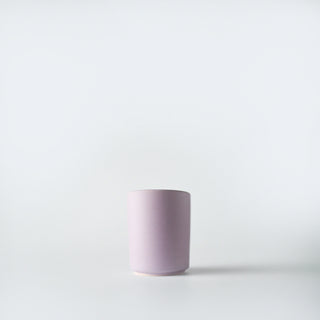 A lavender colored votive sized container against a white background