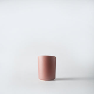 A blurred blushed colored votive against a white background