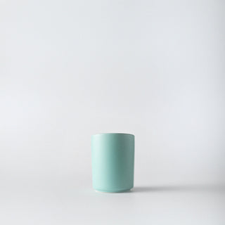 A seafoam green ceramic container with a white background