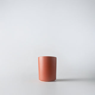 A rust orange colored ceramic container against a white background