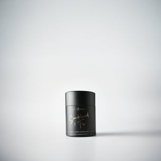 A petite black  candle holder with the text 'Sandalwood & Fir' written in rose gold, displayed against a white background